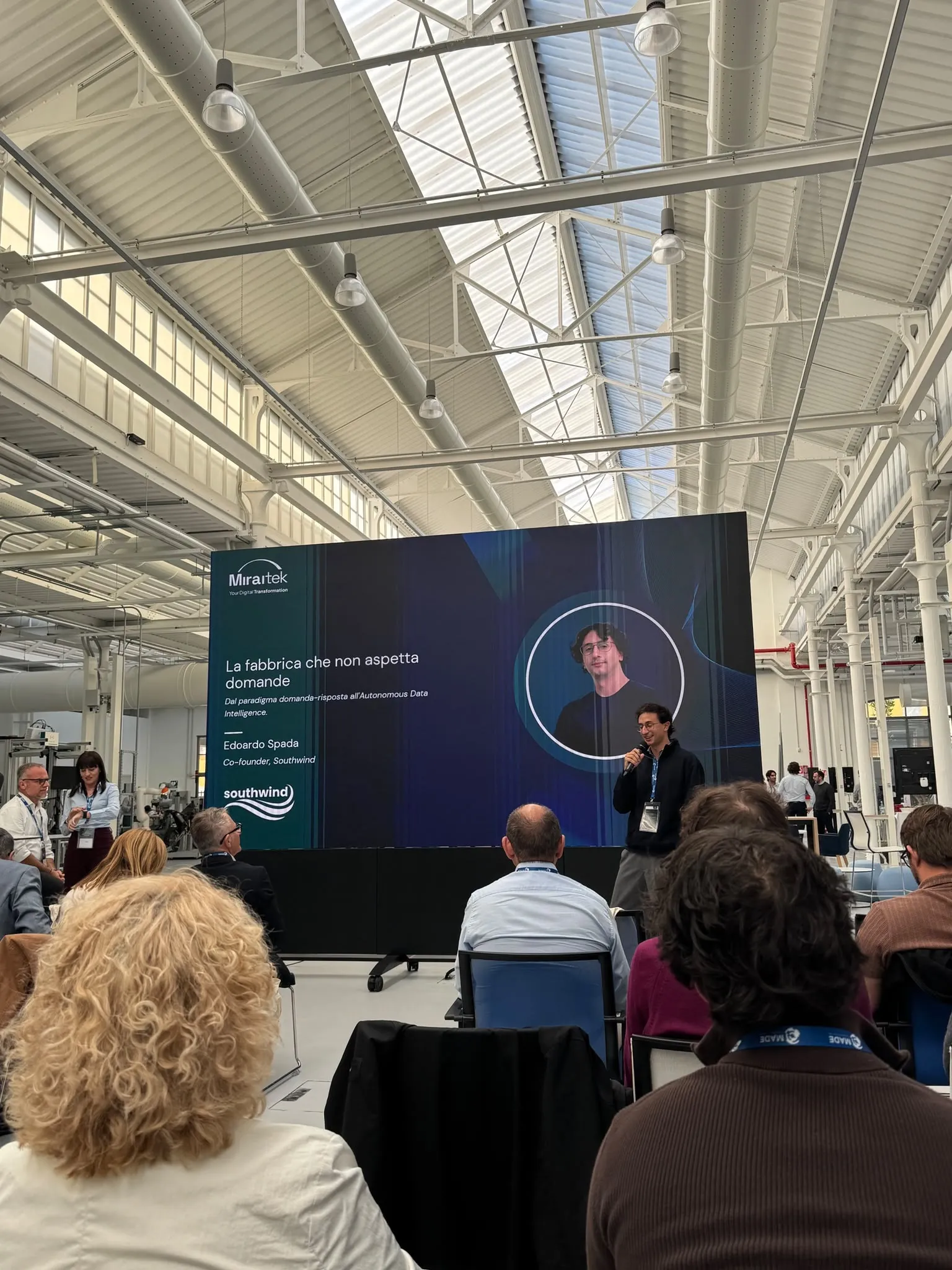 Edoardo Spada sul palco del MADE, con la slide «La fabbrica che non aspetta domande»